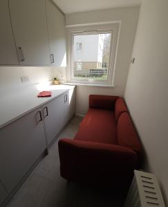 a small kitchen with a red couch and a window at Modern Flat near Central London! in London