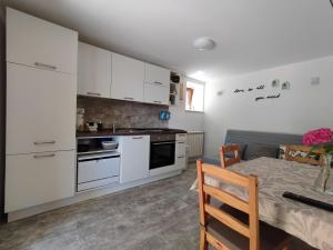 a kitchen with white cabinets and a table and a dining room at Skulka Apartment - Cres Island in Orlec