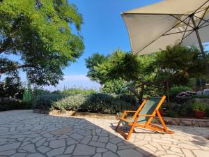 a chair and an umbrella sitting on a patio at Skulka Apartment - Cres Island in Orlec