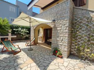 a patio with an umbrella and a table and chairs at Skulka Apartment - Cres Island in Orlec