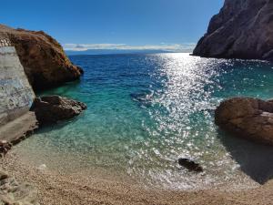 a beach with blue water and rocks on the shore at Skulka Apartment - Cres Island in Orlec