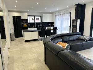 un soggiorno con divano in pelle nera e una cucina di Maison neuve à la montagne a Le Châtelard