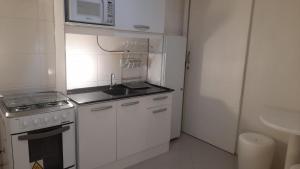 a small white kitchen with a sink and a microwave at Studio climatizado, wifi no centro in Piratuba