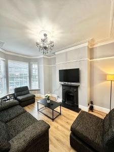 a living room with two couches and a fireplace at Luxury 5 bed Salford home free parking in Manchester
