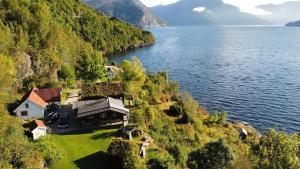 a house on a hill next to a body of water at Charming guest house with amazing view in Kvam