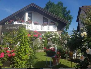 a house with a balcony with flowers in the yard at Ferienwohnung Schindele am Bodensee in Langenargen