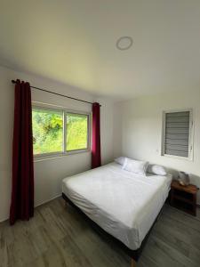 a bedroom with a white bed and a window at Ânani - Mirimiri Lodge in Tevaitoa