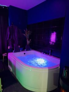 a bathroom with a tub with a purple lighting at Love Room la Vida in Condé-sur-Noireau +33 photos