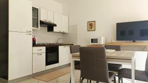 a kitchen with white cabinets and a table with chairs at Casa Vacanza Margherita in Assemini