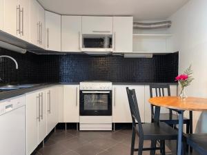 Una cocina con gabinetes blancos y una mesa con sillas. en Märsta Apartment Hotel, en Märsta