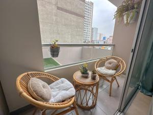 a balcony with two chairs and two tables and a window at Céntrico departamento en Lima in Lima