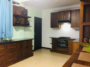 a kitchen with wooden cabinets and a stove top oven at Galle MK Villa in Galle +15 photos