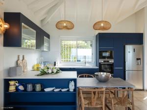 a kitchen with blue cabinets and a table with chairs at Chez Paulette à distance à pied de la plage et piscine chauffée in Friar's Bay