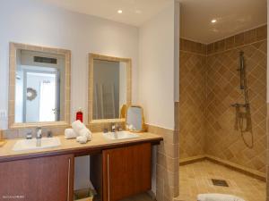 a bathroom with two sinks and a shower at Chez Paulette à distance à pied de la plage et piscine chauffée in Friar's Bay