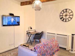 a living room with a tv and a couch and a table at Two-bedroom Cottage - Sandstone Garden Patio - Free Parking - Pets Welcome in Ingrow