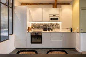 a kitchen with white cabinets and a stove top oven at Sloth Loft Montmartre 2025 Refresh in Paris