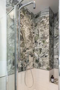 a shower in a bathroom with a stone wall at Sloth Loft Montmartre 2025 Refresh in Paris