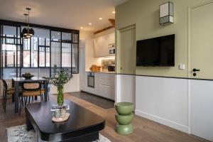 a kitchen and living room with a table and a tv at Sloth Loft Montmartre 2025 Refresh in Paris +24 photos