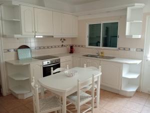 a kitchen with white cabinets and a table and chairs at Albufeira INN - Mulatinho V3 in Olhos de Água +34 photos