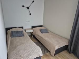 two beds in a room with a clock on the wall at Torowa 2a Apartamenty El-Bema in Biała Podlaska