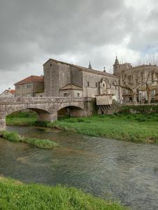 a bridge over a river in front of a building at Casa Marisa Padron, Camino de Santiago in Padrón