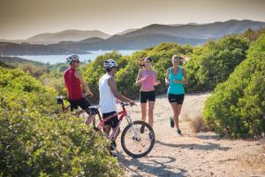 a group of people standing on a trail with bikes at Chia Laguna - Hotel Village in Chia