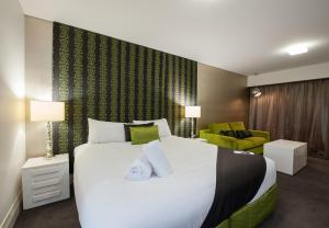 um quarto com uma grande cama branca com toques de verde em City Golf Club Motel em Toowoomba