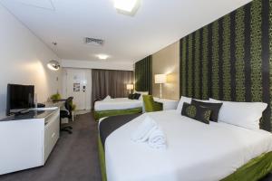 a hotel room with two beds and a television at City Golf Club Motel in Toowoomba