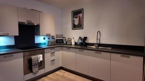 a kitchen with white cabinets and a sink at City Center 1 Bed Flat in Peterborough +5 photos