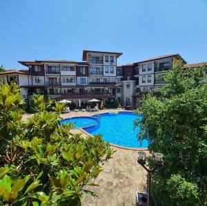 a swimming pool in front of some buildings at Beachfront Apartment with Garden at Venid Sandy Beach - Apartment Marina Dinevi View in Sveti Vlas