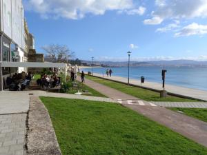 un grupo de personas sentadas en bancos cerca del agua en Casa "O Forte" en la playa, Espectacular ubicación, en Cangas de Morrazo