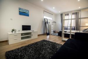 a living room with a couch and a tv on a wall at Casa Mãe Deus - House Azores in Ponta Delgada