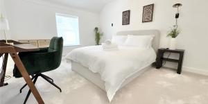 a bedroom with a white bed with a desk and a chair at Chapel House Luxury Apartments Hoylake in Birkenhead