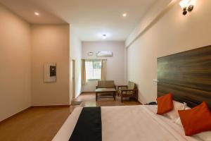 迈索尔Townhouse J K Golden Embassy的一间酒店房间，里面有一张床和一把椅子