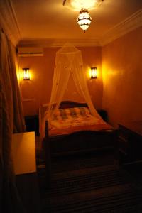 a bedroom with a bed with a canopy in a dark room at Auberge Cavaliers in Aït Baha