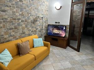 a living room with a yellow couch and a tv at Casa di Flavio in Castelsardo