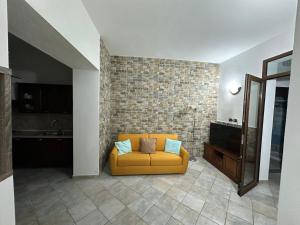 a yellow couch in a room with a brick wall at Casa di Flavio in Castelsardo