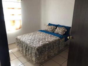 a bedroom with a bed with a blanket and pillows at Recidencial Pacifico in Rincon de Guayabitos