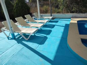 a row of lounge chairs sitting next to a swimming pool at Recidencial Pacifico in Rincon de Guayabitos