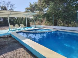 a swimming pool with two chairs and a gazebo at Recidencial Pacifico in Rincon de Guayabitos