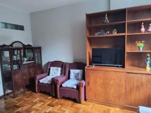 a living room with two chairs and a flat screen tv at Apto Clássico, Centro de Friburgo, em frente à Pça Getúlio Vargas e pertinho do Teleférico e da Pça Suspiro - Muito bem equipado - Aquecedor in Nova Friburgo
