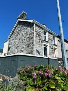 an old stone building with flowers in front of it at Pen Y Berth in Porthmadog