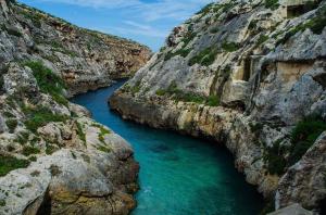 um rio entre dois penhascos rochosos com água azul em Farmhouse Dhyana em Għasri