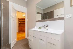 墨尔本Whistling Pines - Bayside Family Stay with Granny Flat的一间白色浴室，配有洗手池和镜子。 更多51张照片