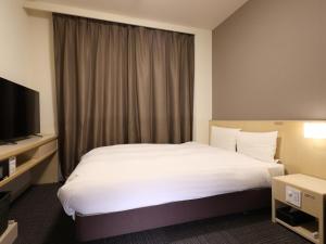 a hotel room with a bed and a television at Dormy Inn Kofu Natural Hot Spring Kaiji no Yu Reopening on February 3rd 2025 in Kofu