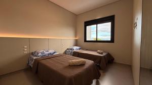 a room with two beds and a window at IA02- 2 Quartos| Centro| Vista Mar| Churrasqueira in Itapoa