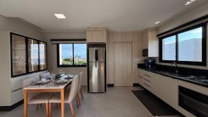 a kitchen with a table and a stainless steel refrigerator at IA02- 2 Quartos| Centro| Vista Mar| Churrasqueira in Itapoa