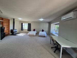 a room with two beds and a desk in it at Cozy FarmStay with Spa in Pokeno