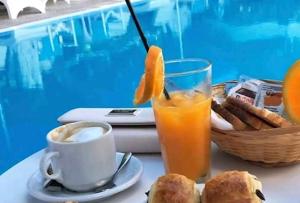 米克诺斯城ELLI TROPiCAL LUXURY SUITES SUNSET-INFINITY POOL- SEA SIDE-NEAR CENTER PARKING的一张桌子,上面放着一杯橙汁和一篮子的食物