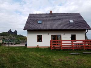 a white house with a red fence in the grass at Apartmány Trosky in Troskovice
